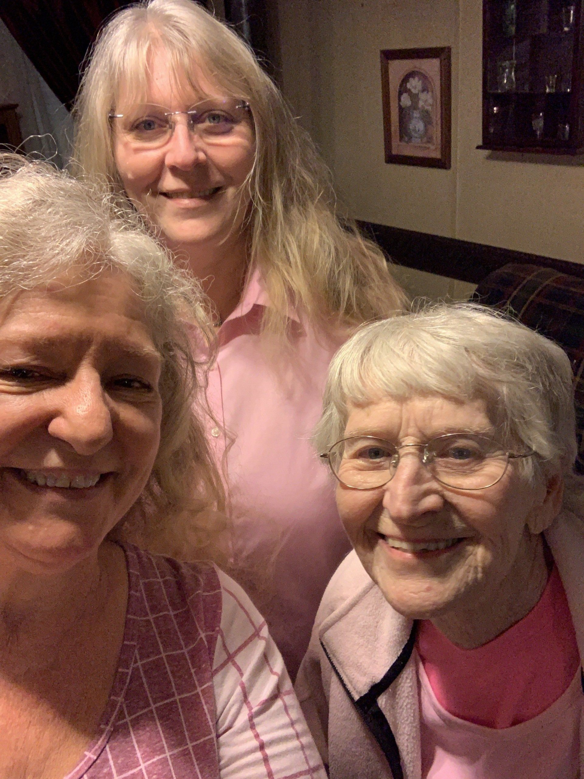 three women are posing for a picture together and smiling for the camera .