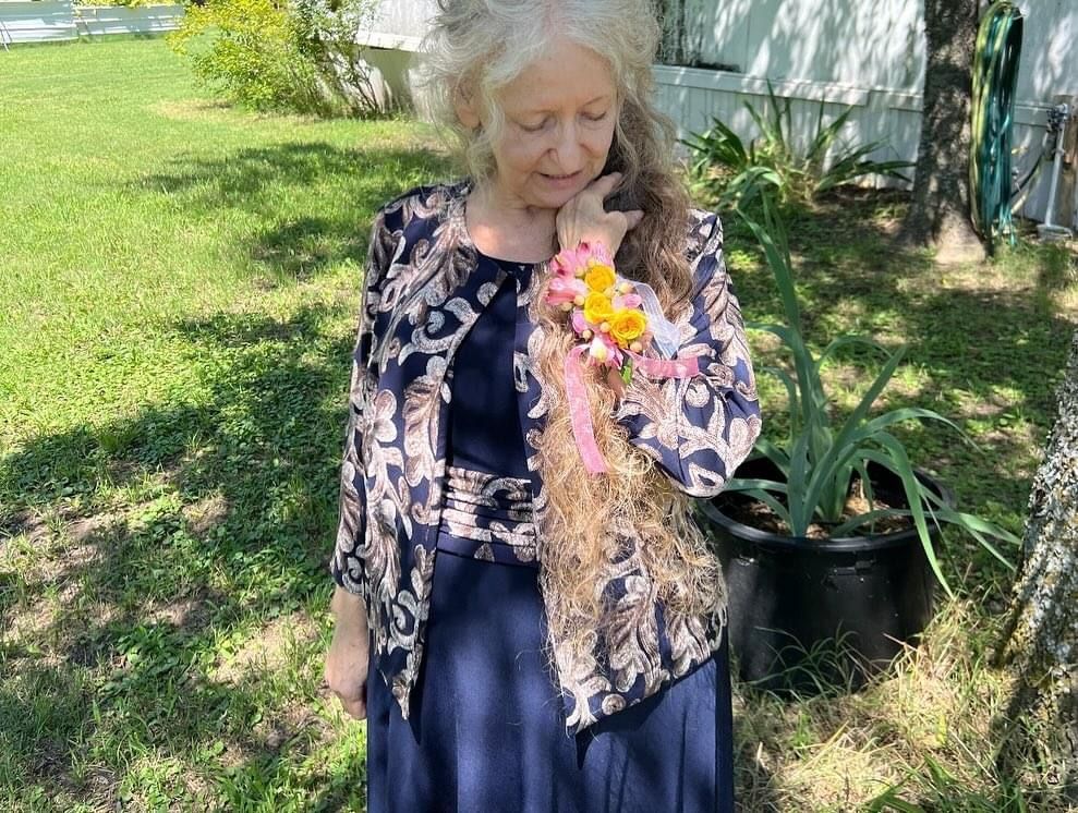 lady with long red and grey hair; with flowers on wrist