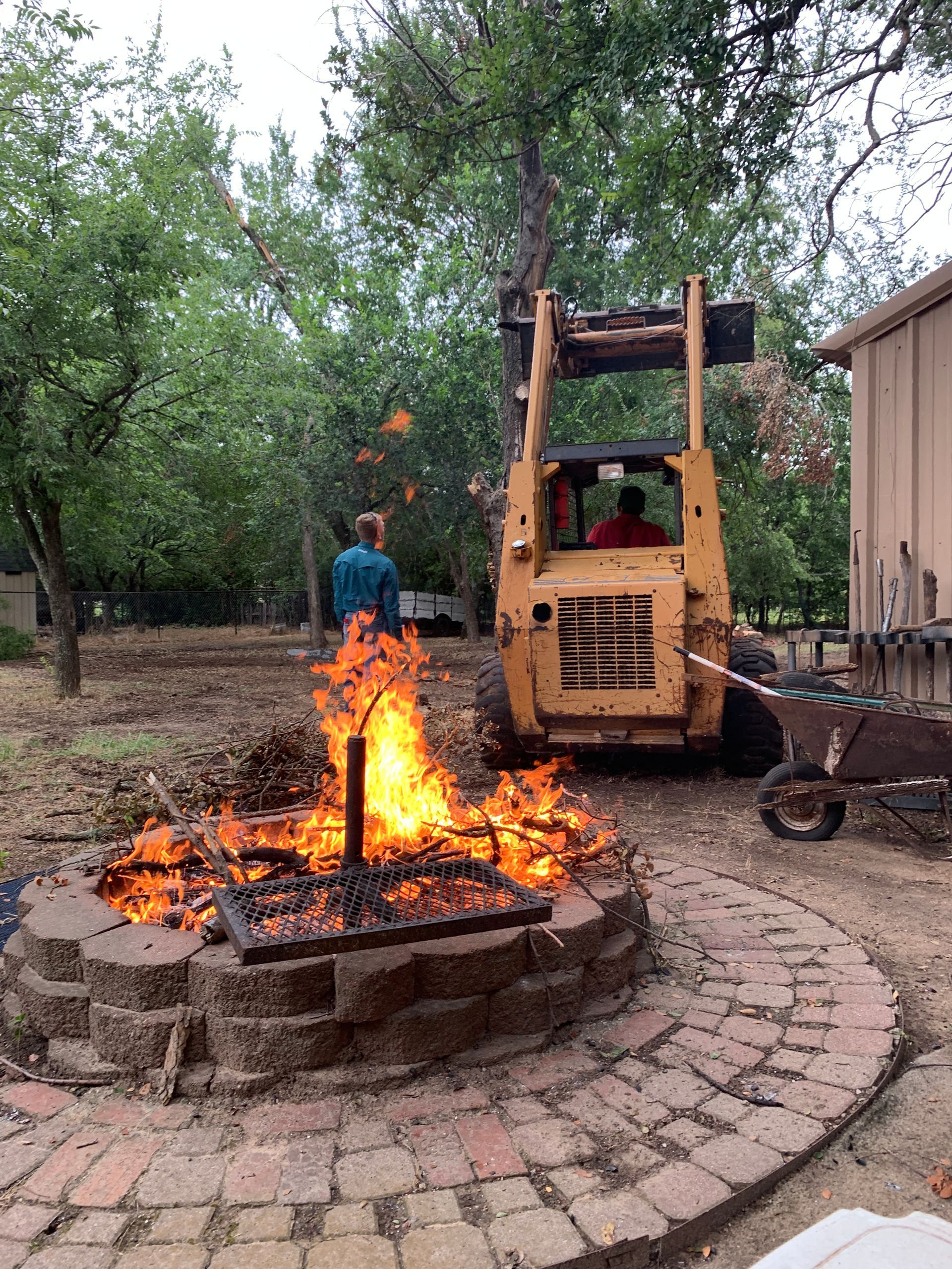 tractor taking down tree, burning limbs in fire pit