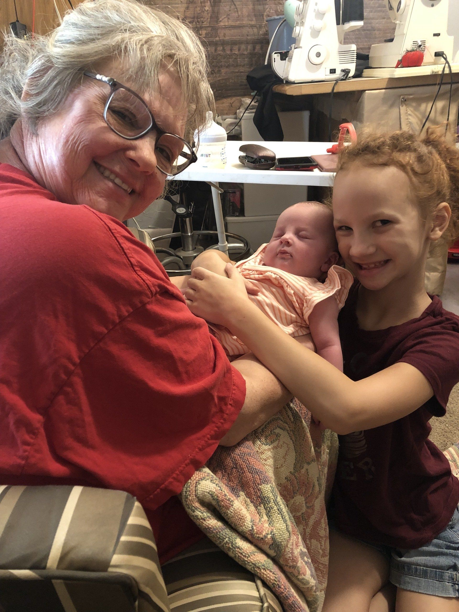 an older woman is holding a baby and two young girls are sitting next to her .
