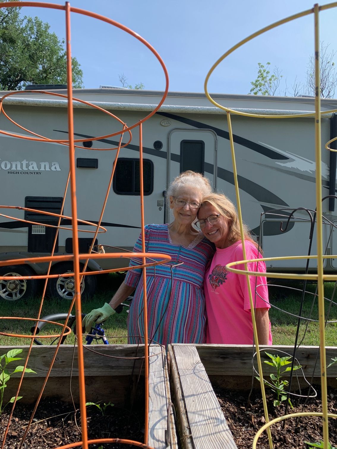 2 sisters hugging behind a garden bed
