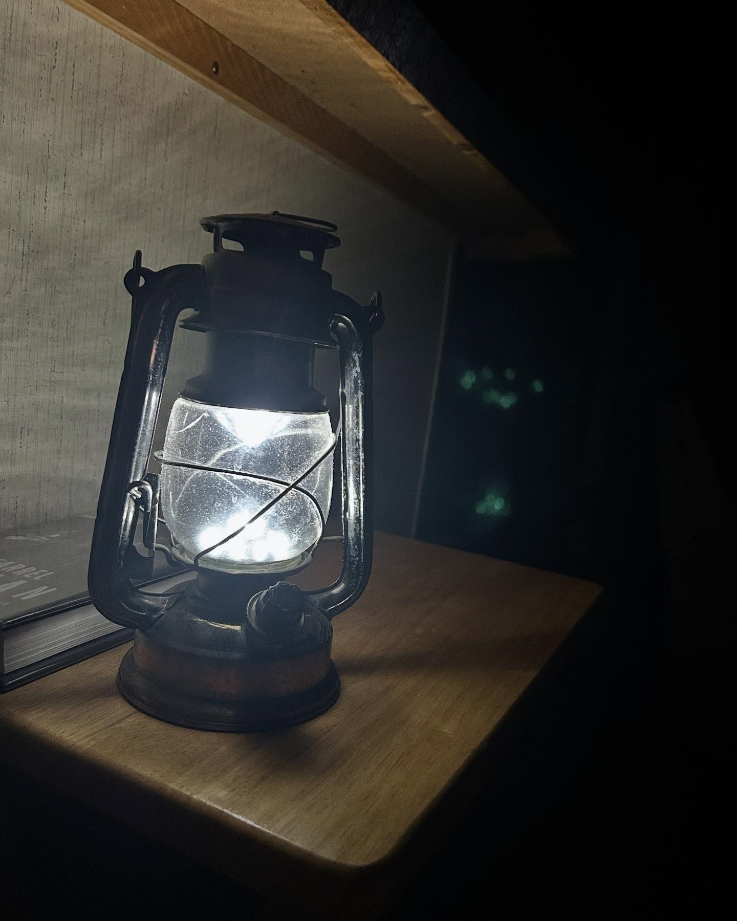 A lantern is lit up on a wooden table