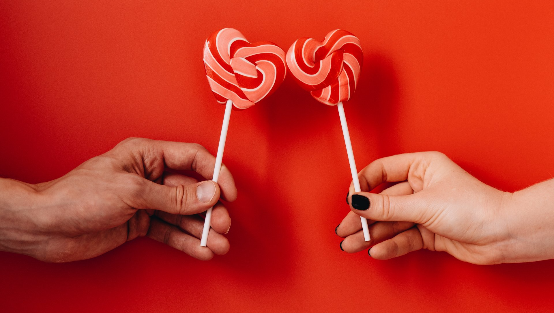 a man and a woman are holding two lollipops in their hands .