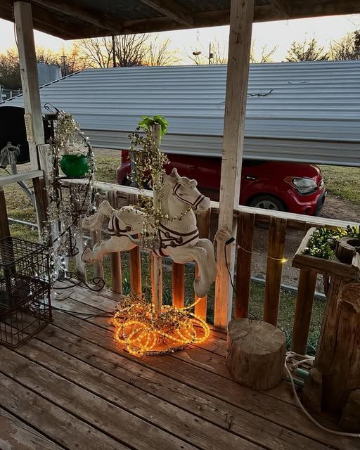 A wooden porch with a merry go round and a red truck in the background.