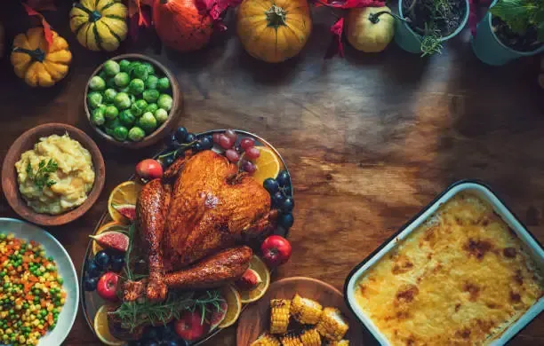 Thanksgiving feast: roasted turkey, side dishes, and pumpkins on a wooden table.