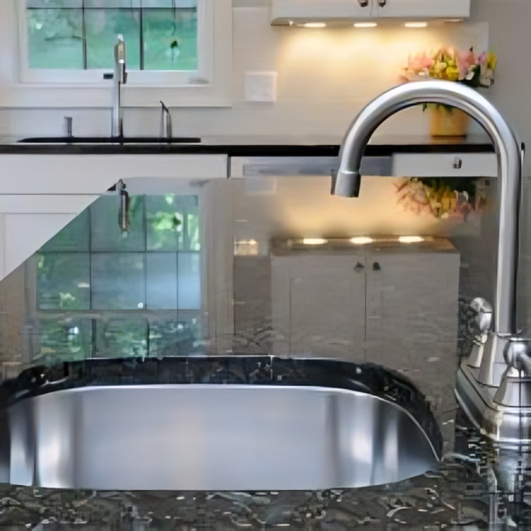 Stainless steel kitchen sink with faucet, granite countertop, white cabinets, and a window in the background.