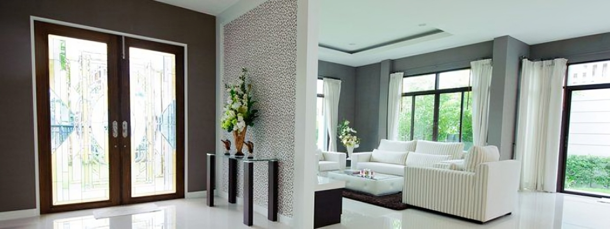 Modern home interior with glass doors, white sofa, and a mosaic accent wall.