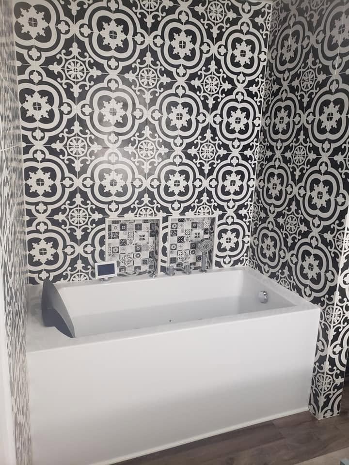 White bathtub in a small bathroom with black-and-white patterned tile walls