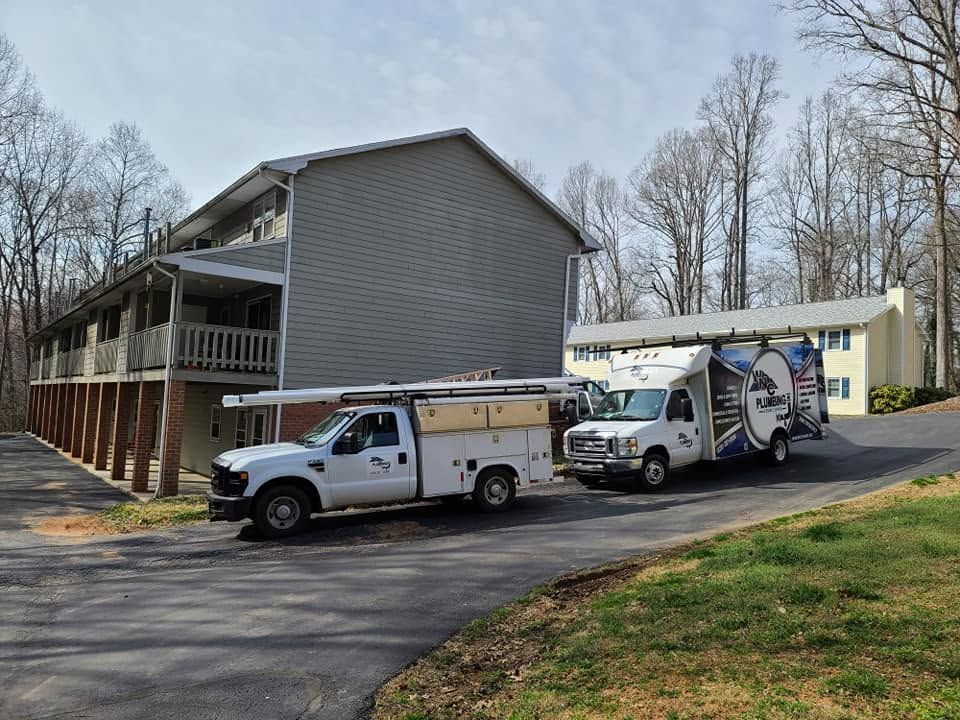 Two utility trucks parked beside a beige apartment building on a paved driveway