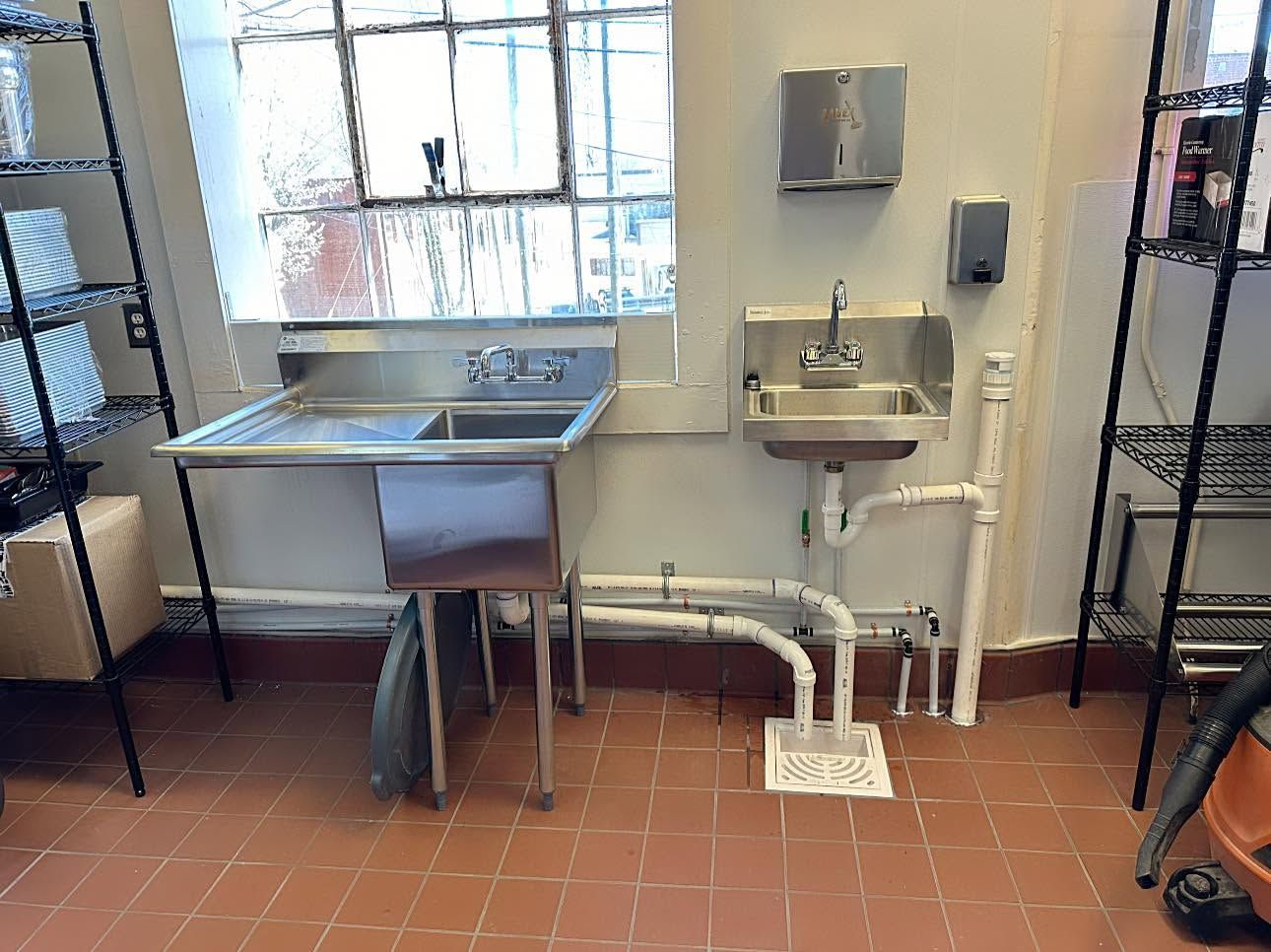Stainless steel utility sink and small wall-mounted sink in a tiled utility room