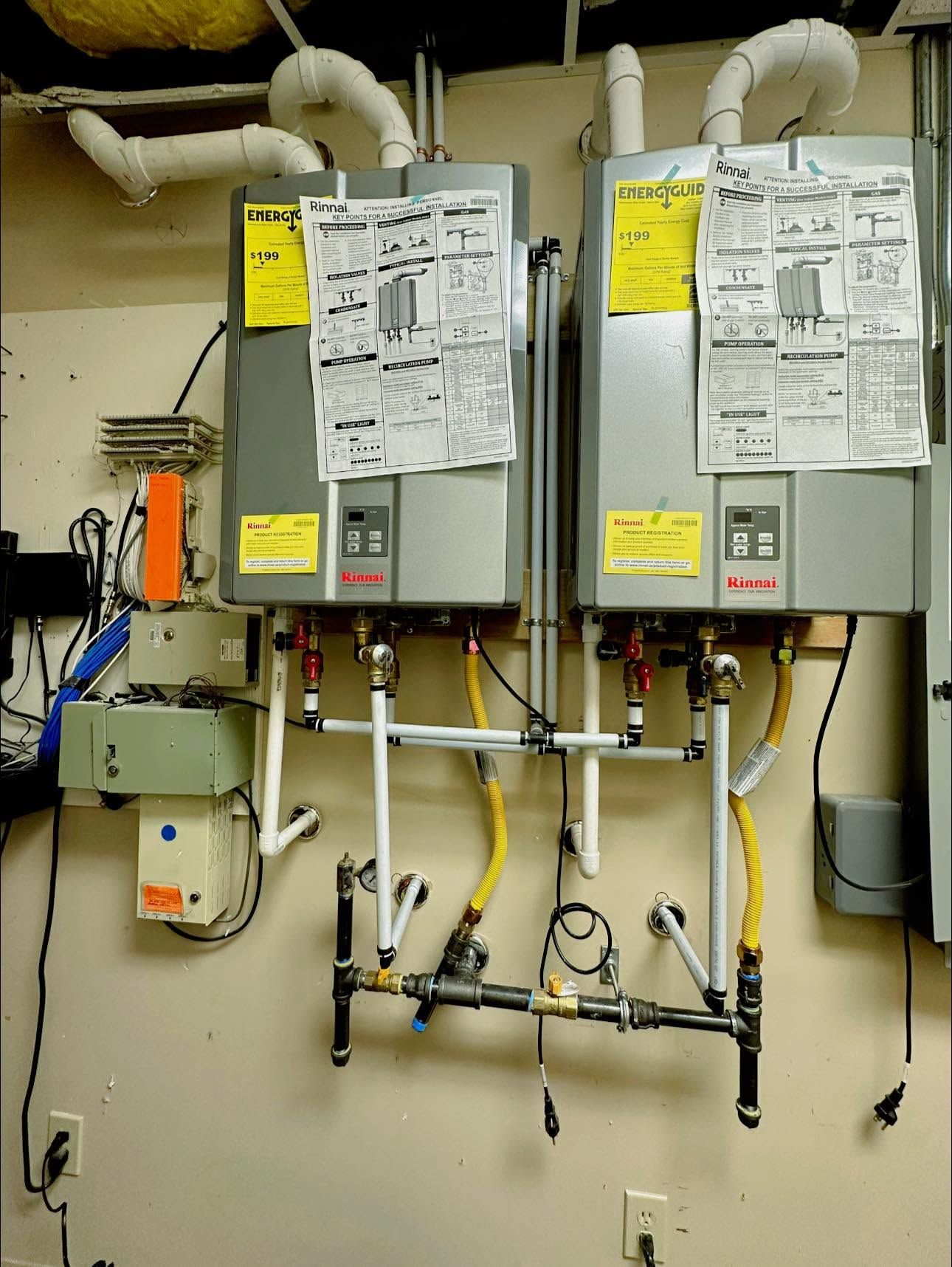 Two gray HVAC/boiler control panels with pipes and wiring in a utility room