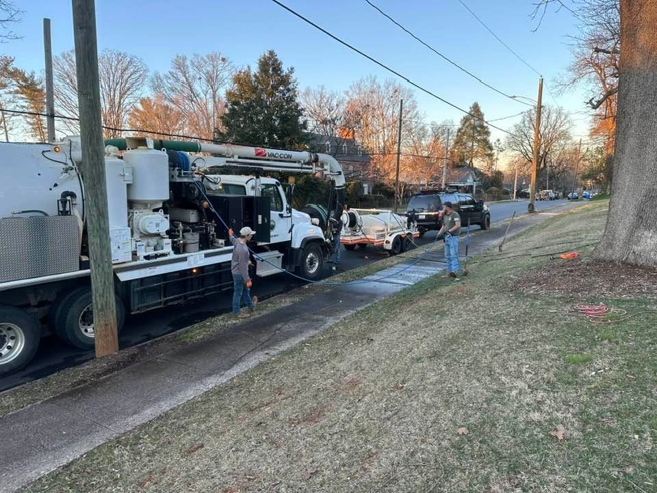 Utility truck and workers on a residential street with utility poles and overhead wires at dusk.