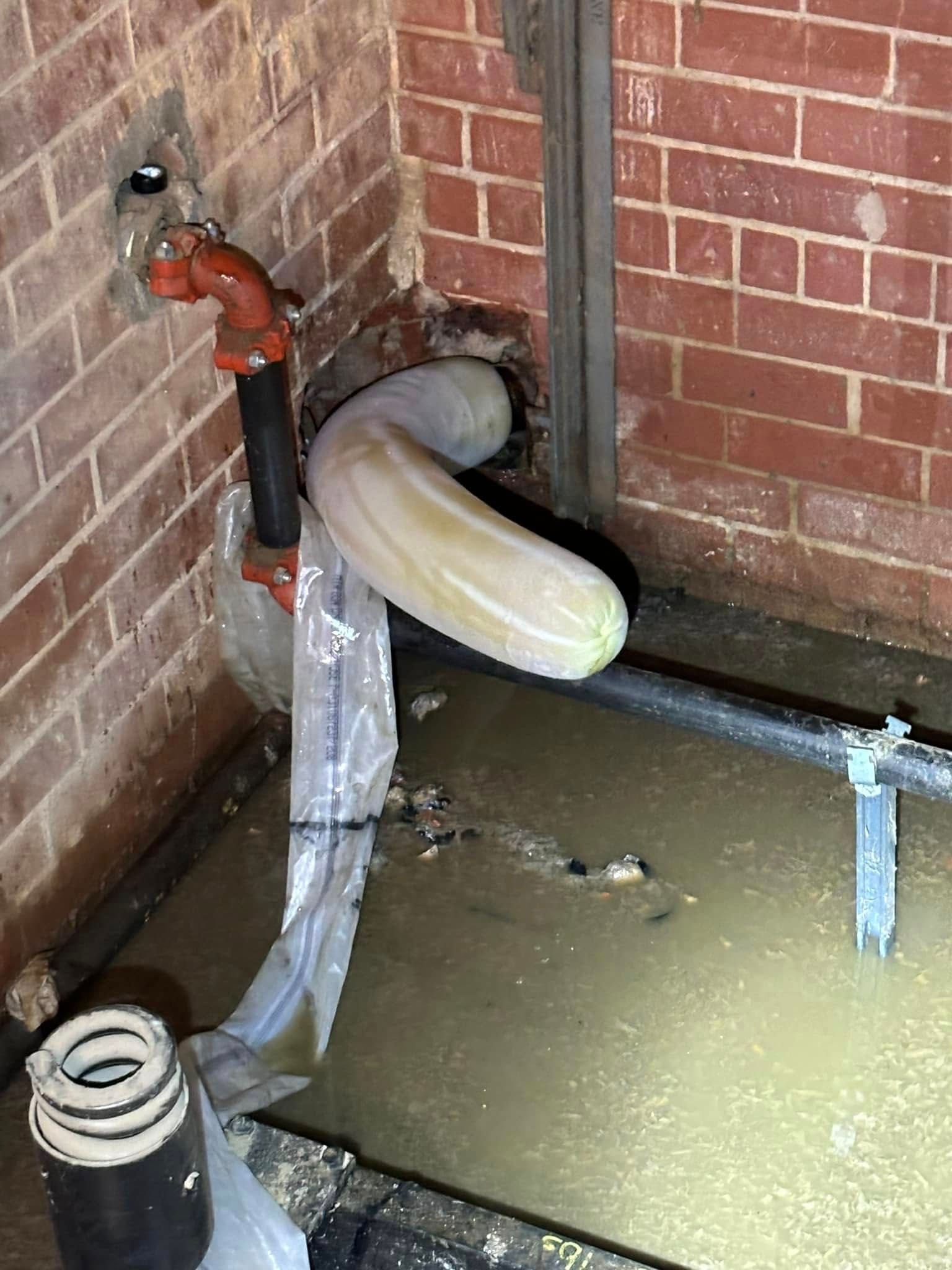 Overfilled toilet in a flooded corner bathroom, with water spilling onto the floor.