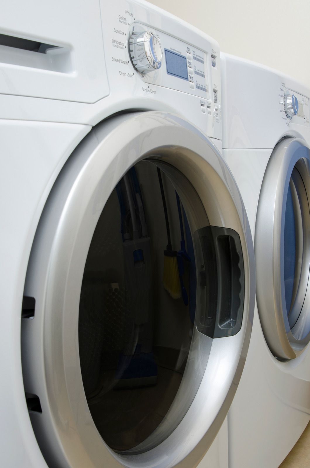 White front-loading washing machines in a laundry room, one door open
