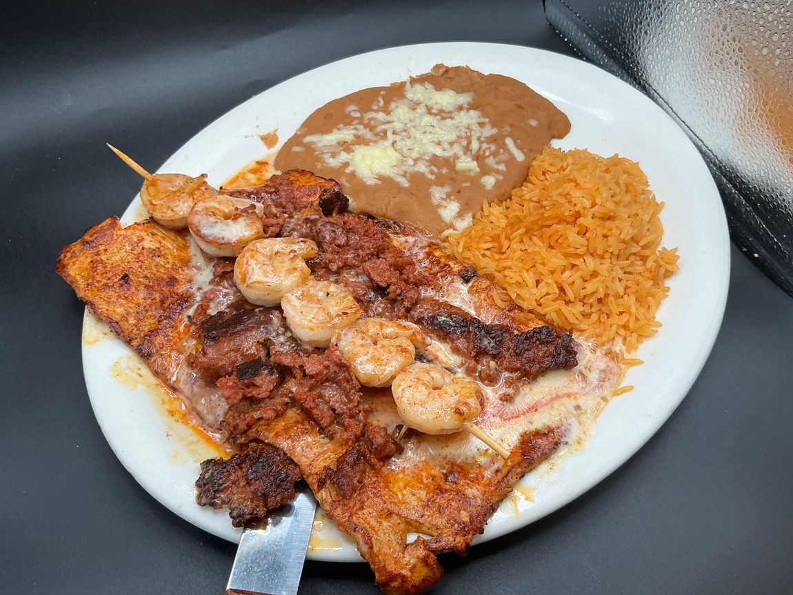 Plate of Mexican food: grilled fish topped with shrimp, chorizo, beans, and rice.