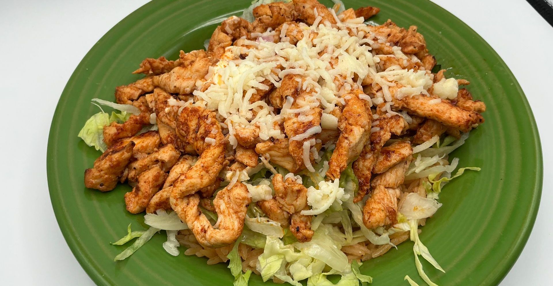 Chicken salad with shredded lettuce and cheese on a green plate.
