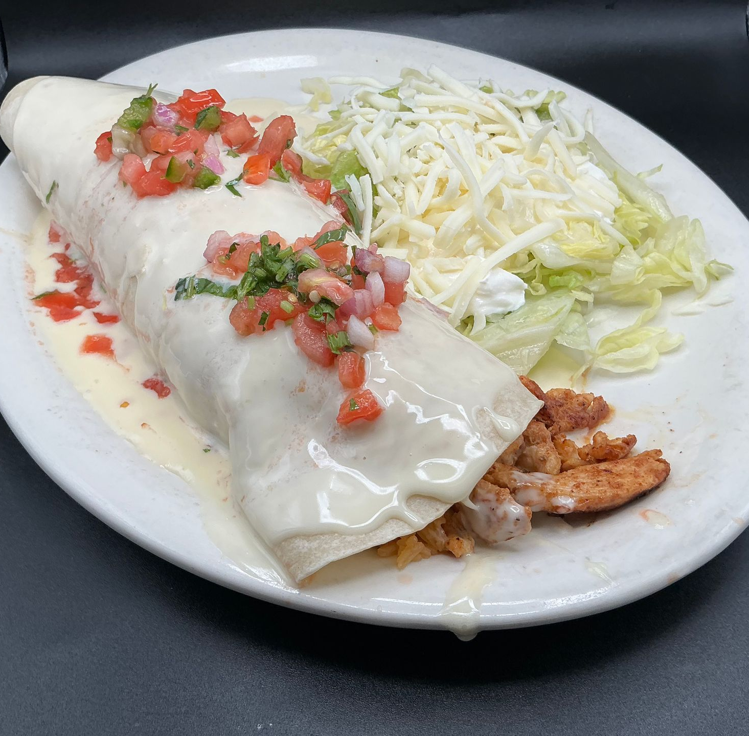 Hand squeezing lime juice onto a taco with toppings and french fries on an orange plate. Bottles of soda and sauces are nearby.