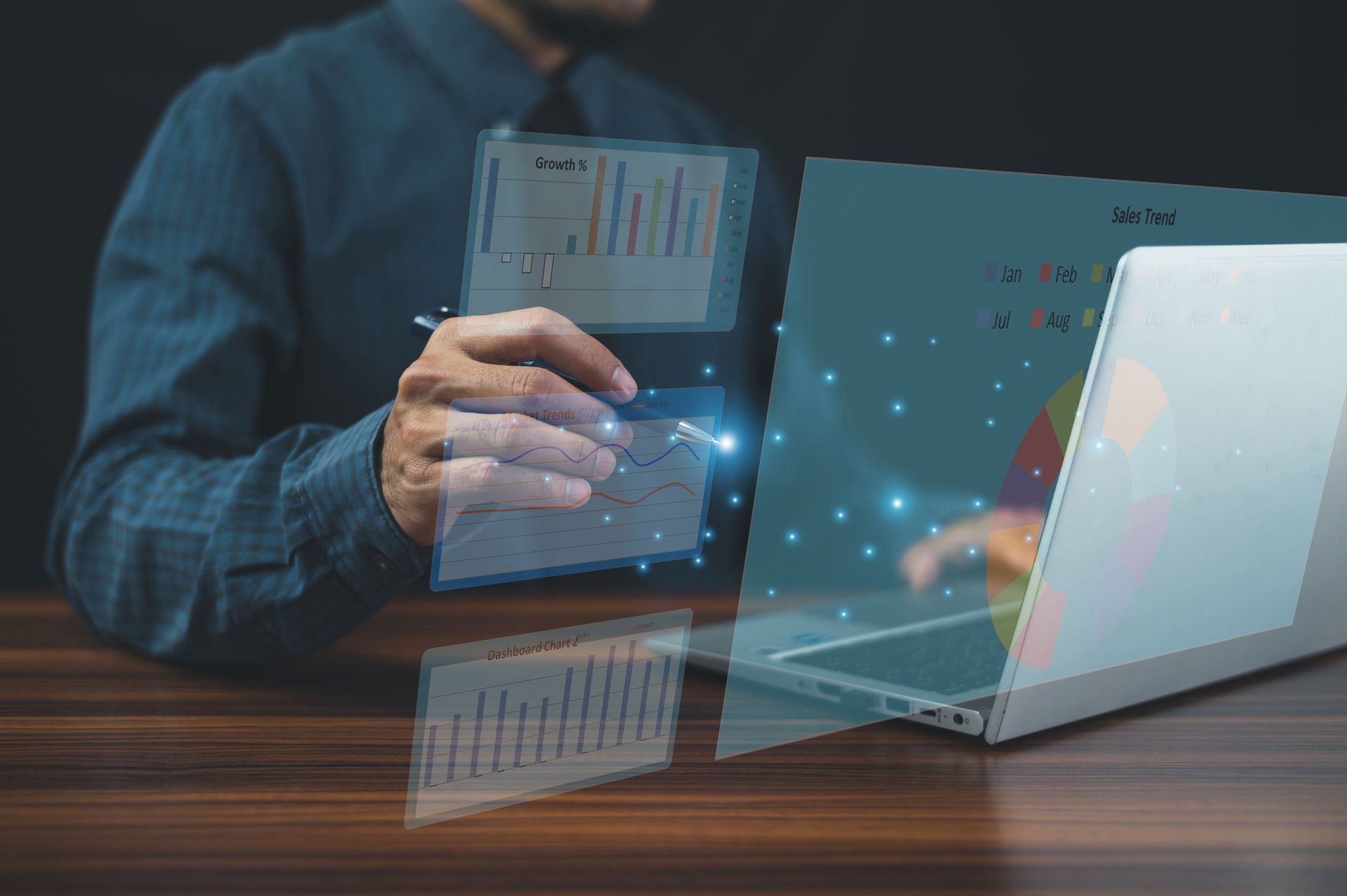 Businessperson using a laptop with transparent data charts and glowing digital panels in an office