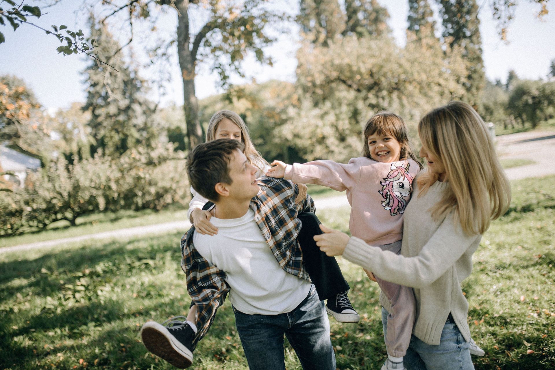 A family is walking through a park holding hands.