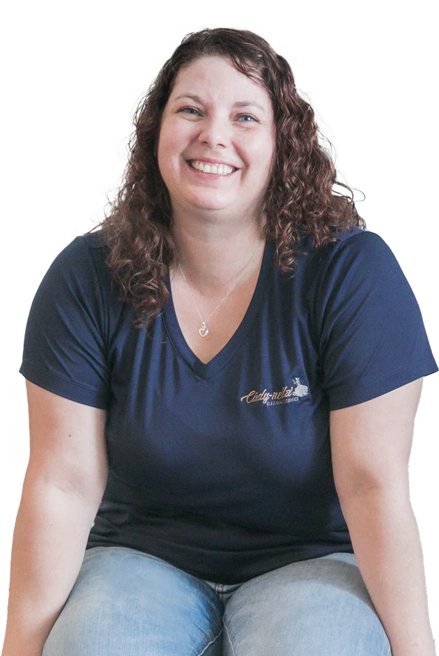 Woman with curly brown hair, wearing a navy V-neck shirt and jeans, smiling.