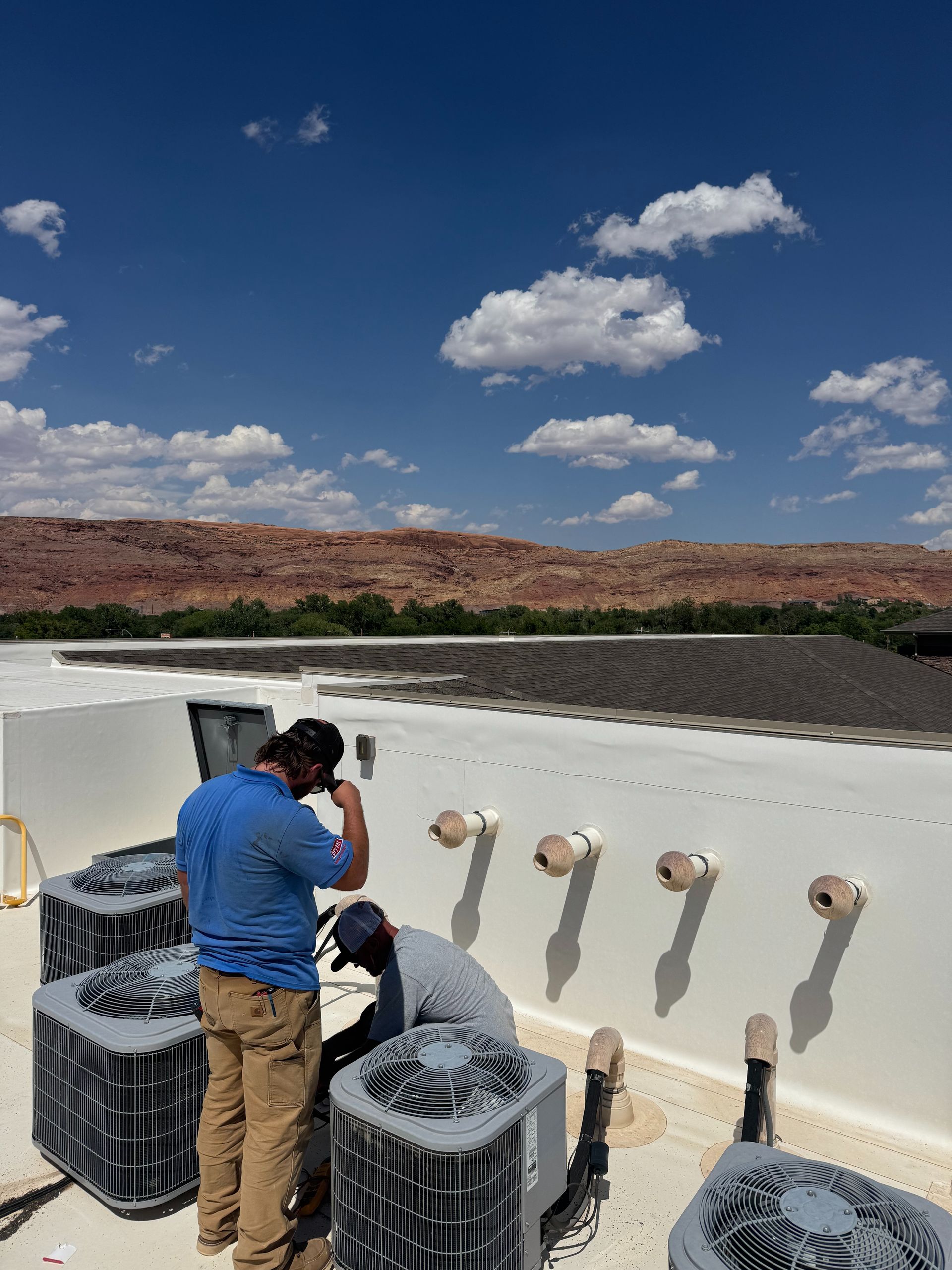 Person photographing a white concrete structure in a desert landscape under a blue sky with clouds