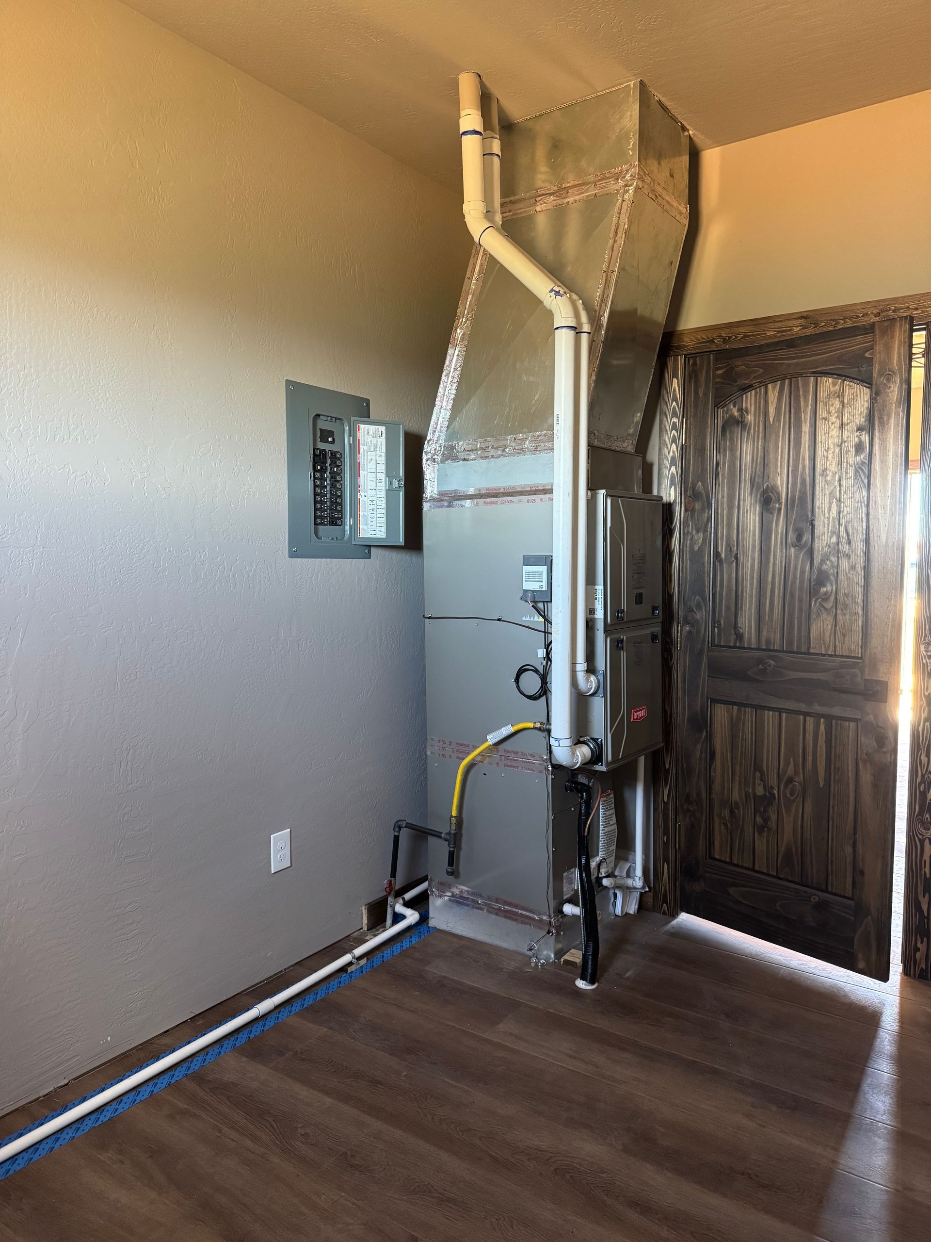 Residential elevator lift in a room beside a wooden door, with a wall-mounted control panel.