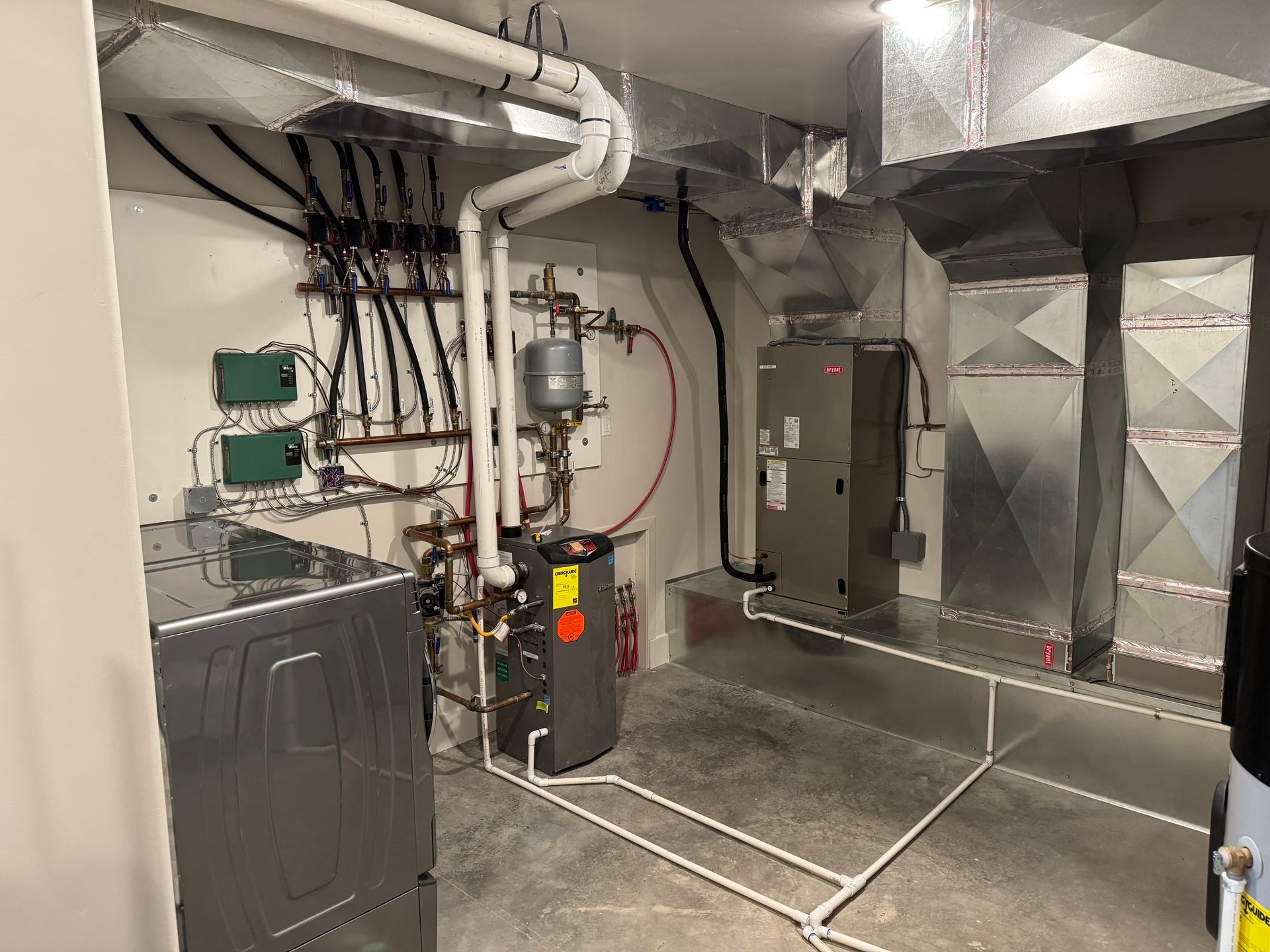 Mechanical room with furnace, ducts, pipes, and industrial HVAC equipment on concrete floor