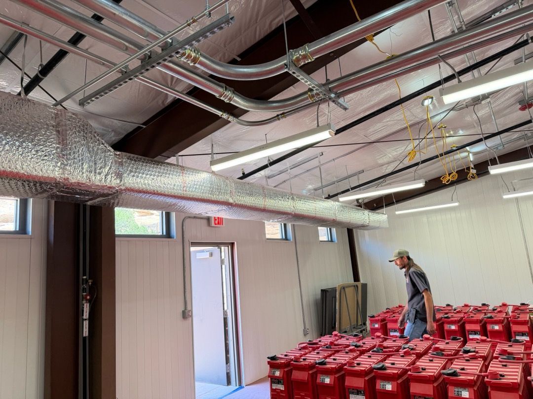 Warehouse-like hall with exposed ceiling ducts, red chairs, and a person standing near the back wall