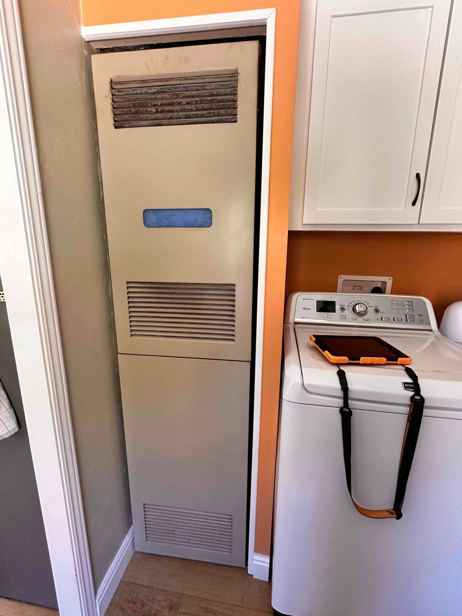 Laundry room with a beige utility cabinet beside a white washing machine and dryer.