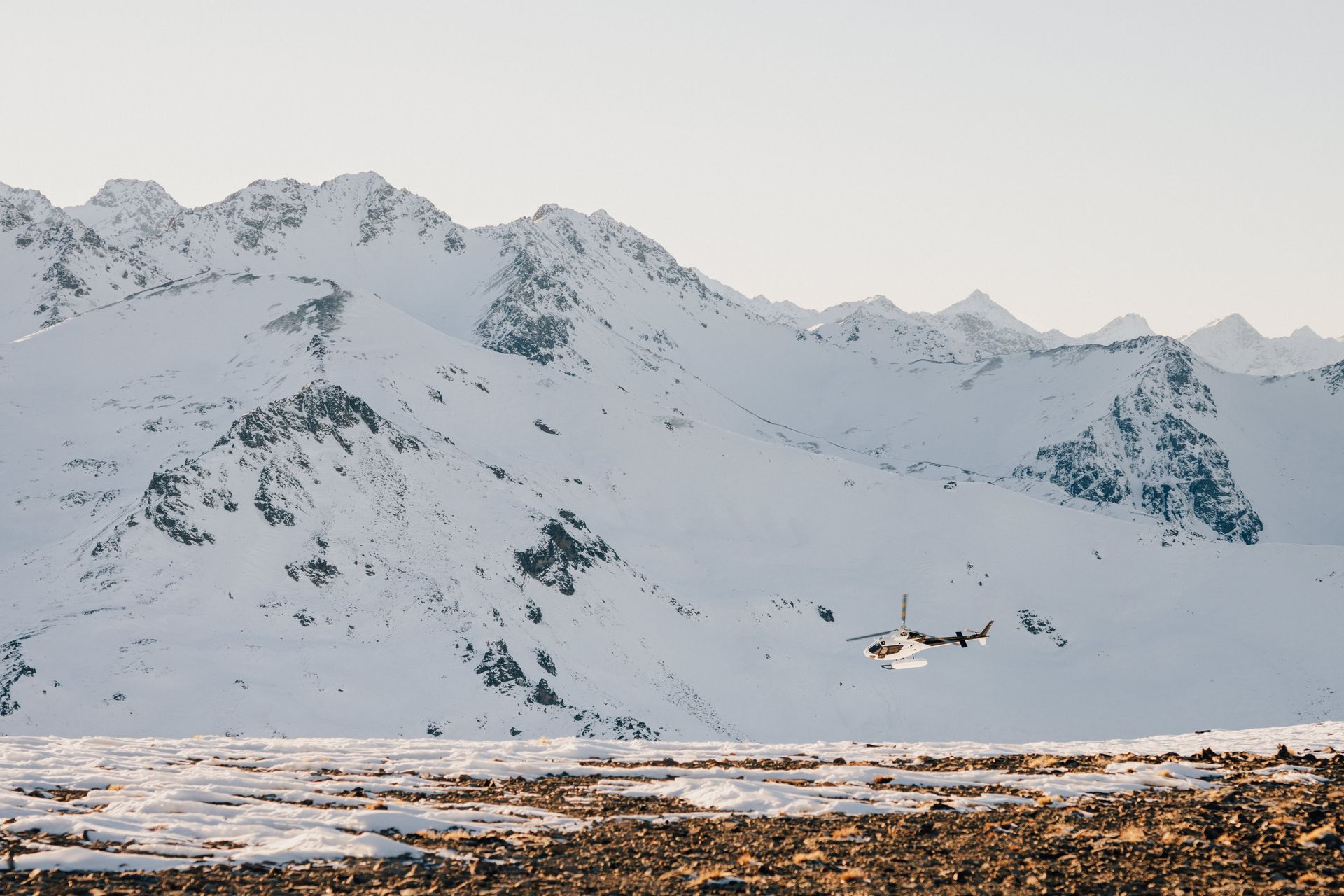 A plane is flying over a snowy mountain range.
