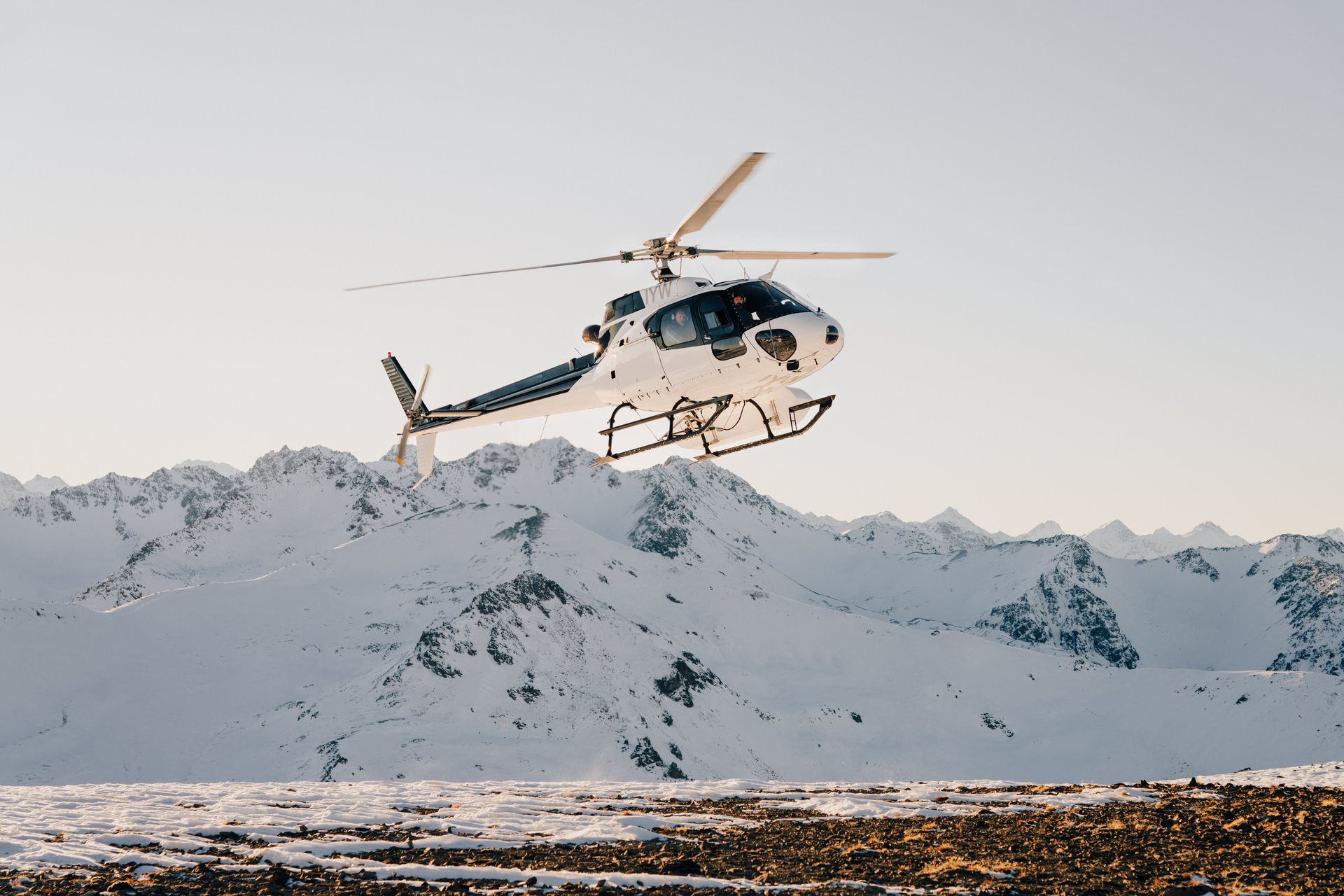 A helicopter is flying over a snowy mountain.