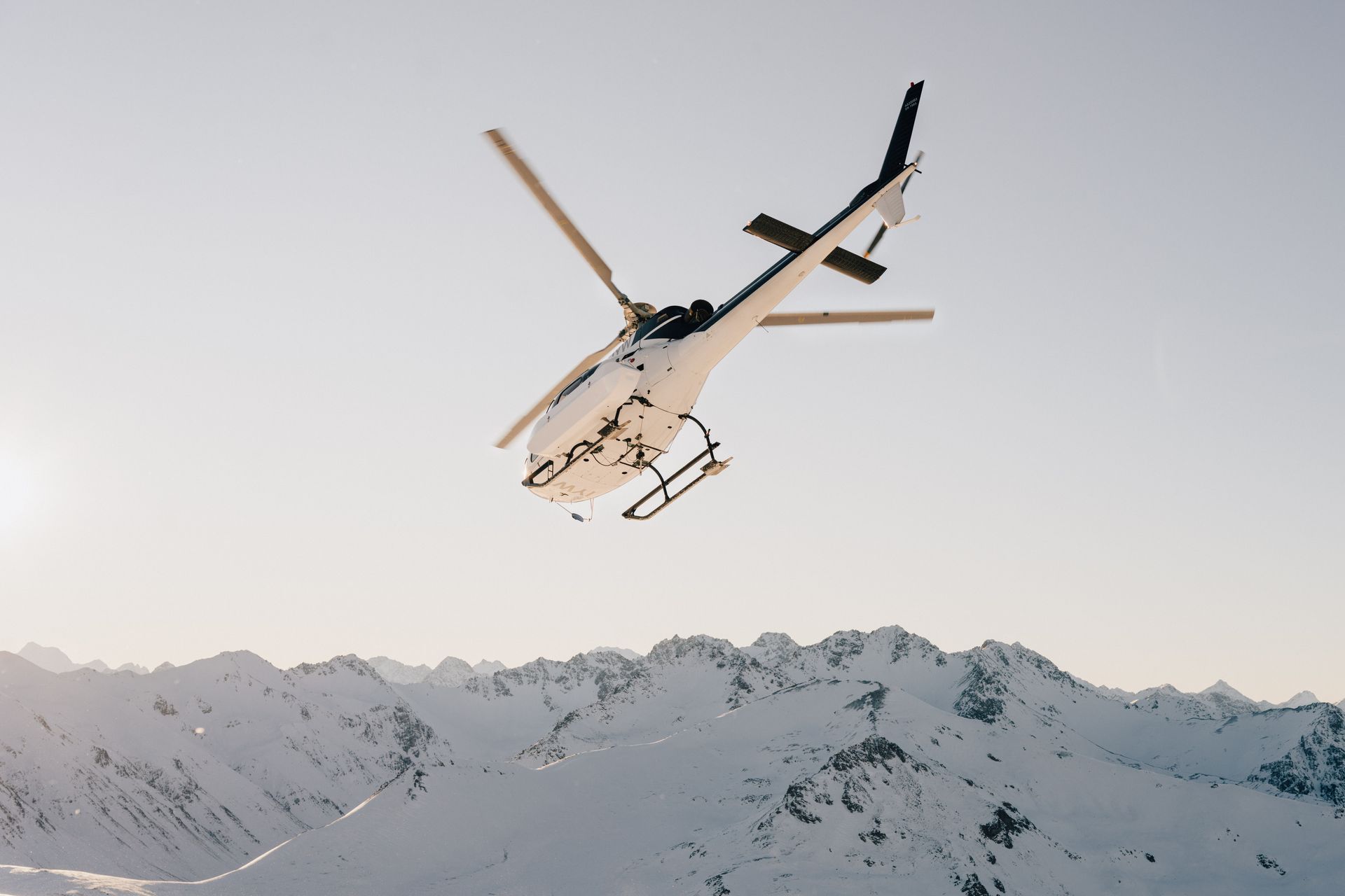 A helicopter is flying over a snowy mountainHigh Country Outfitters