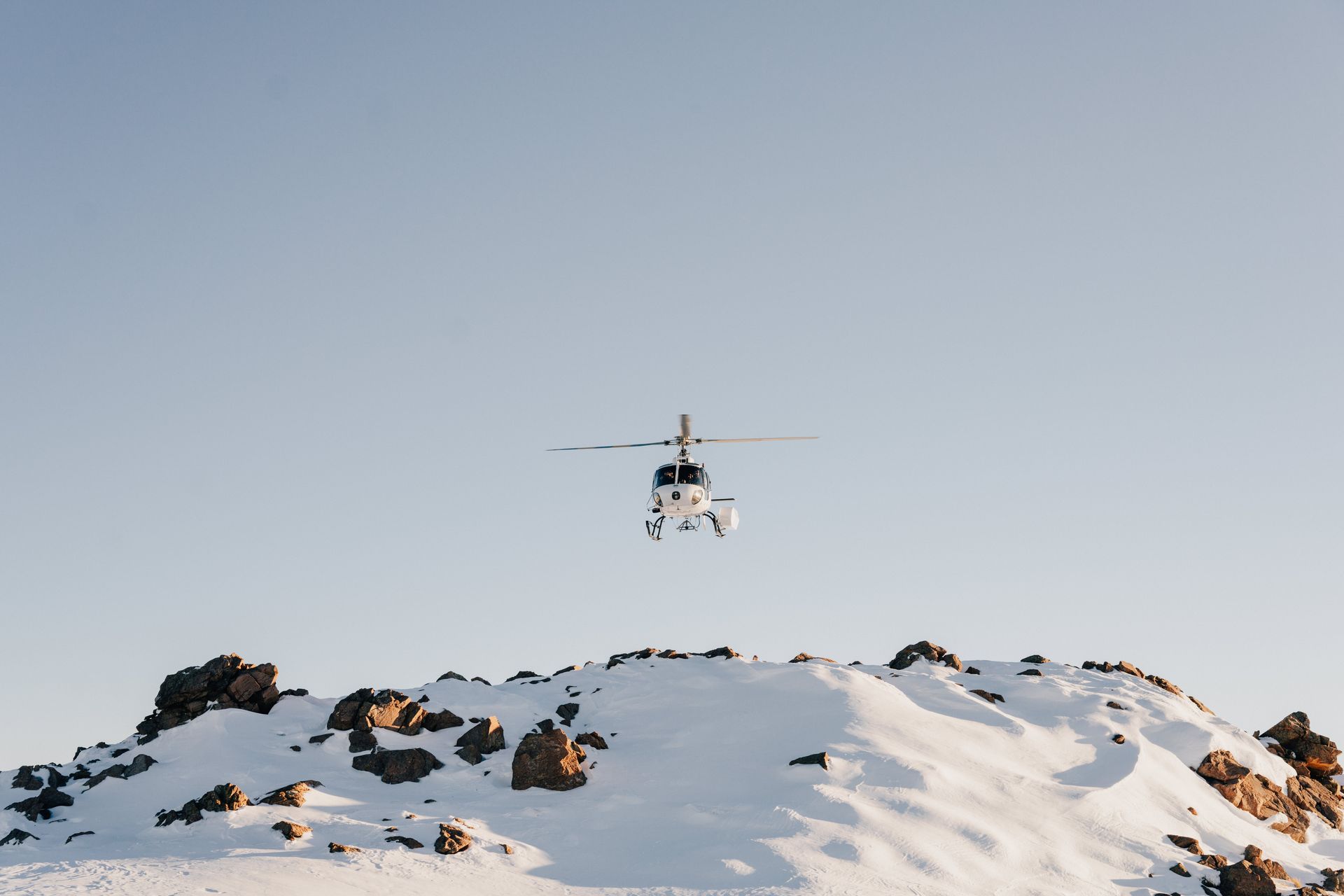 A helicopter is flying over a snowy mountain.