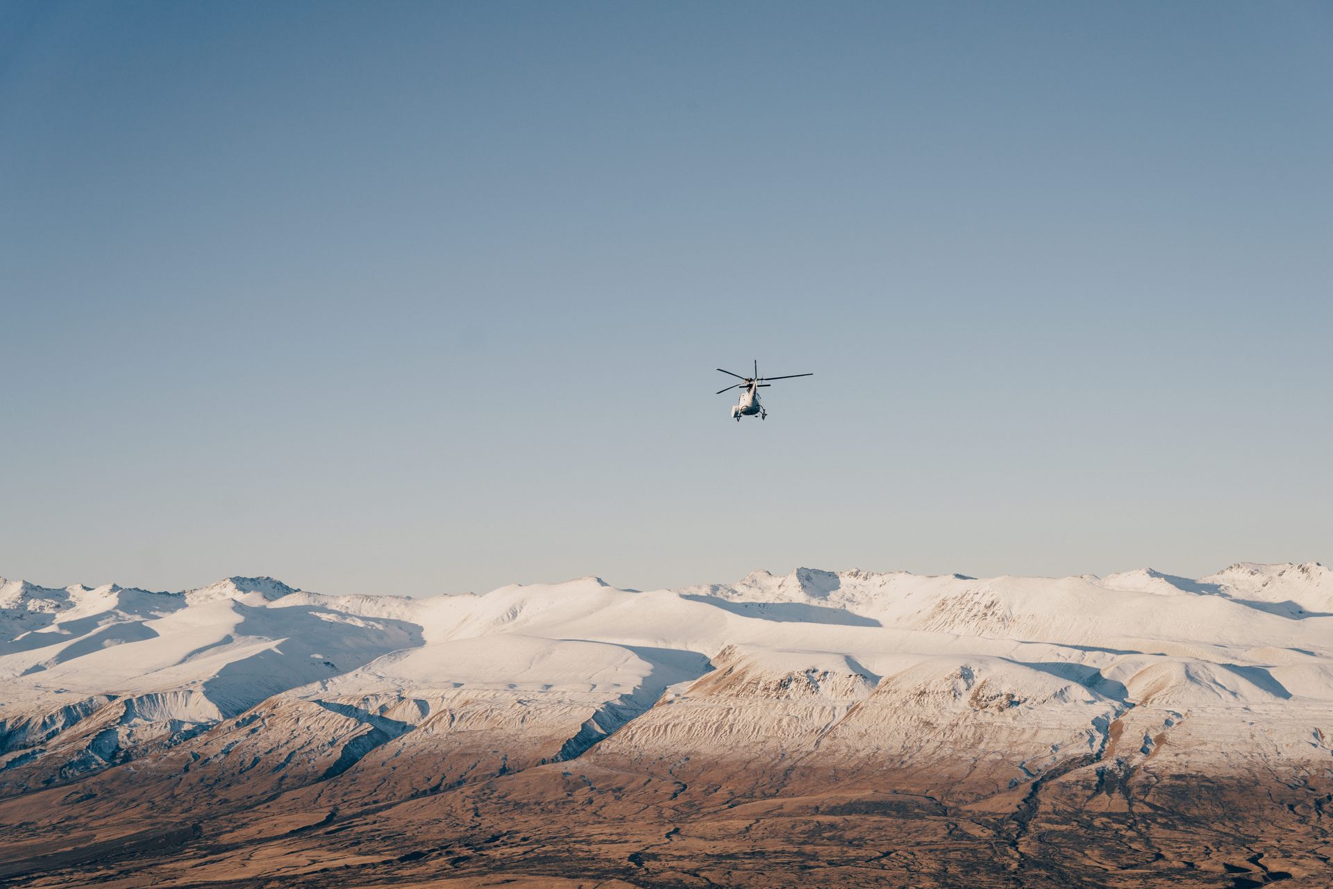 A person is flying over a snowy mountain range.