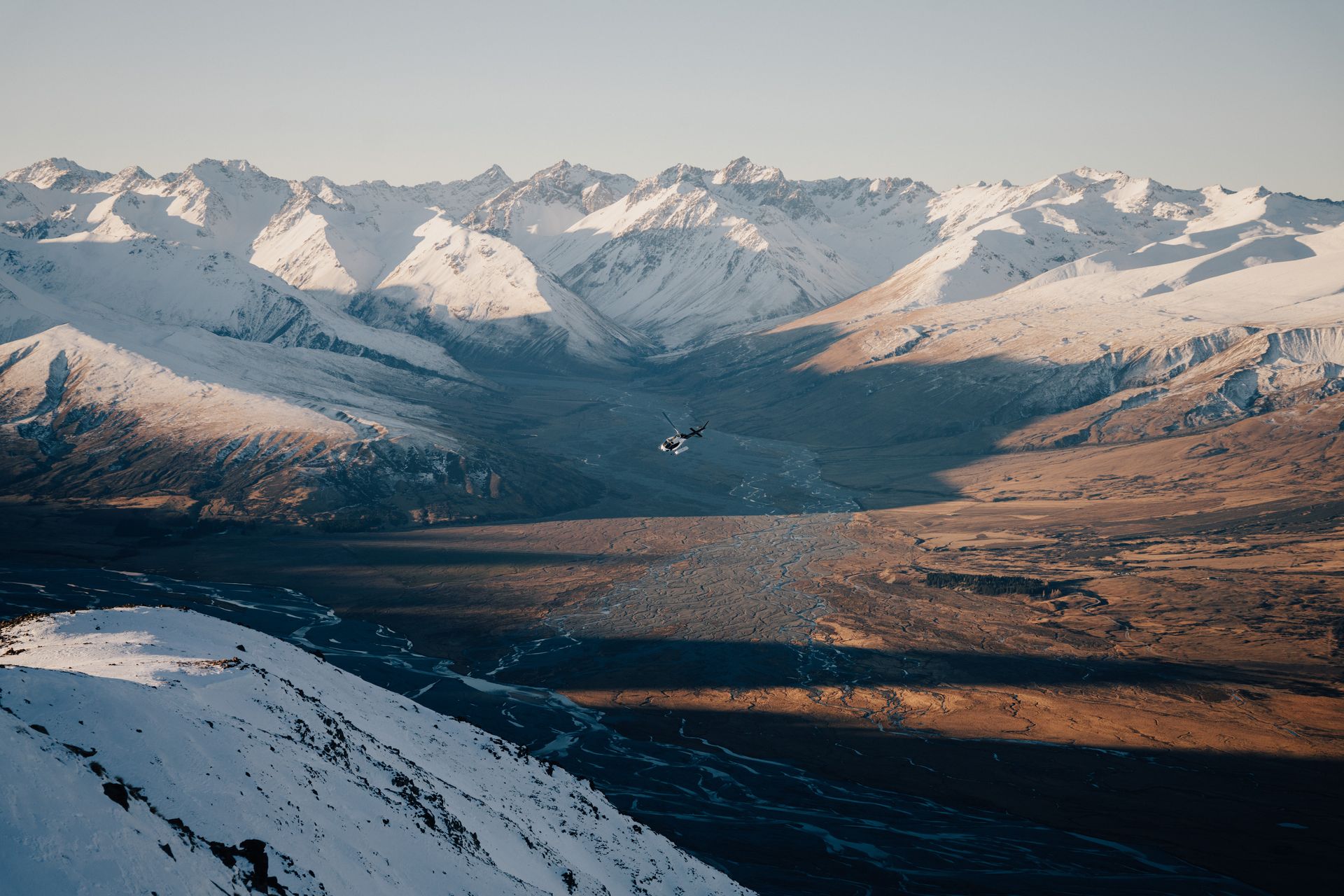 A helicopter is flying over a snowy mountain range.High Country Outfitters