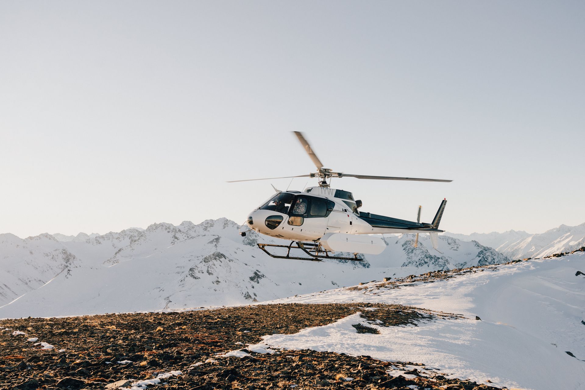 A helicopter is flying over a snowy mountain.High Country Outfitters