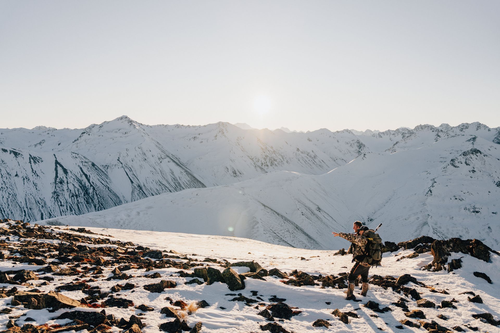 A person is standing on top of a snow covered mountain. High Country Outfitters