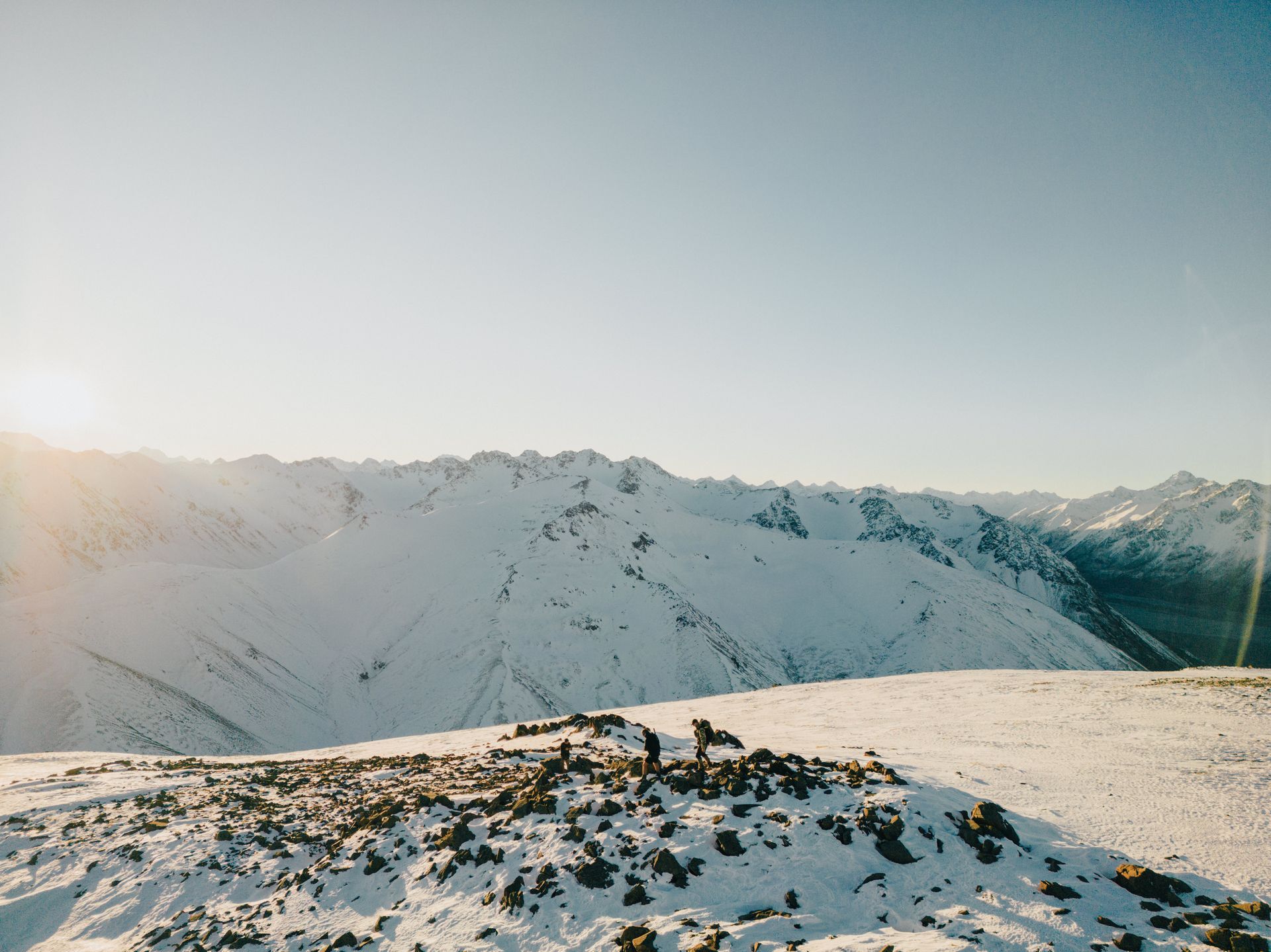 The sun is shining through the snow on the mountains