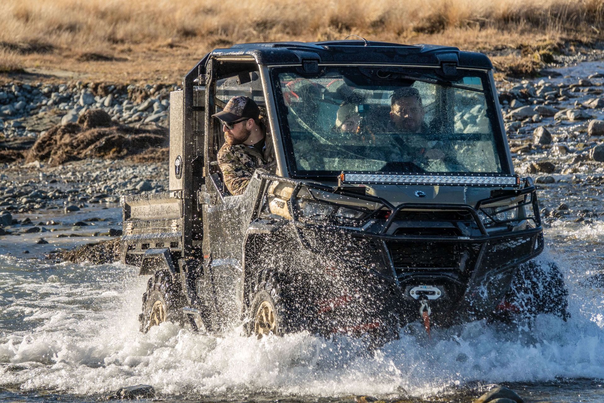 A man is driving a utility vehicle through a river.High Country Outfitters