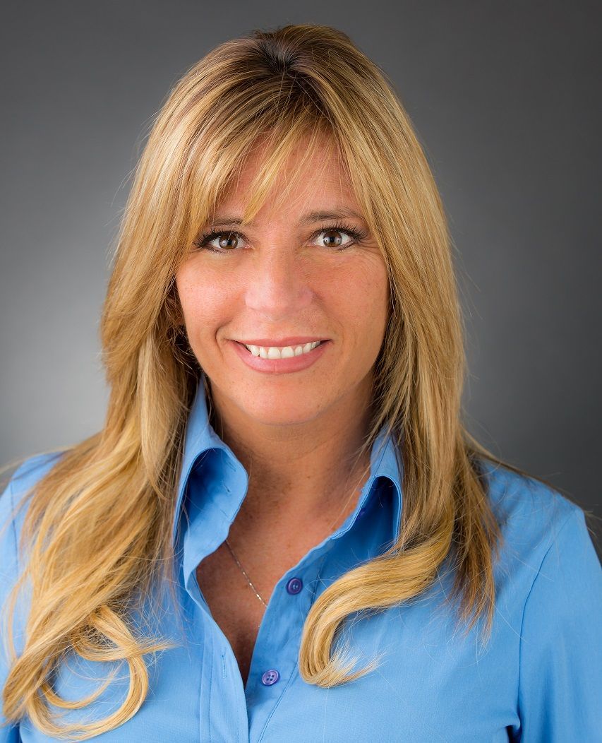 Smiling person in a blue shirt against a gray studio background