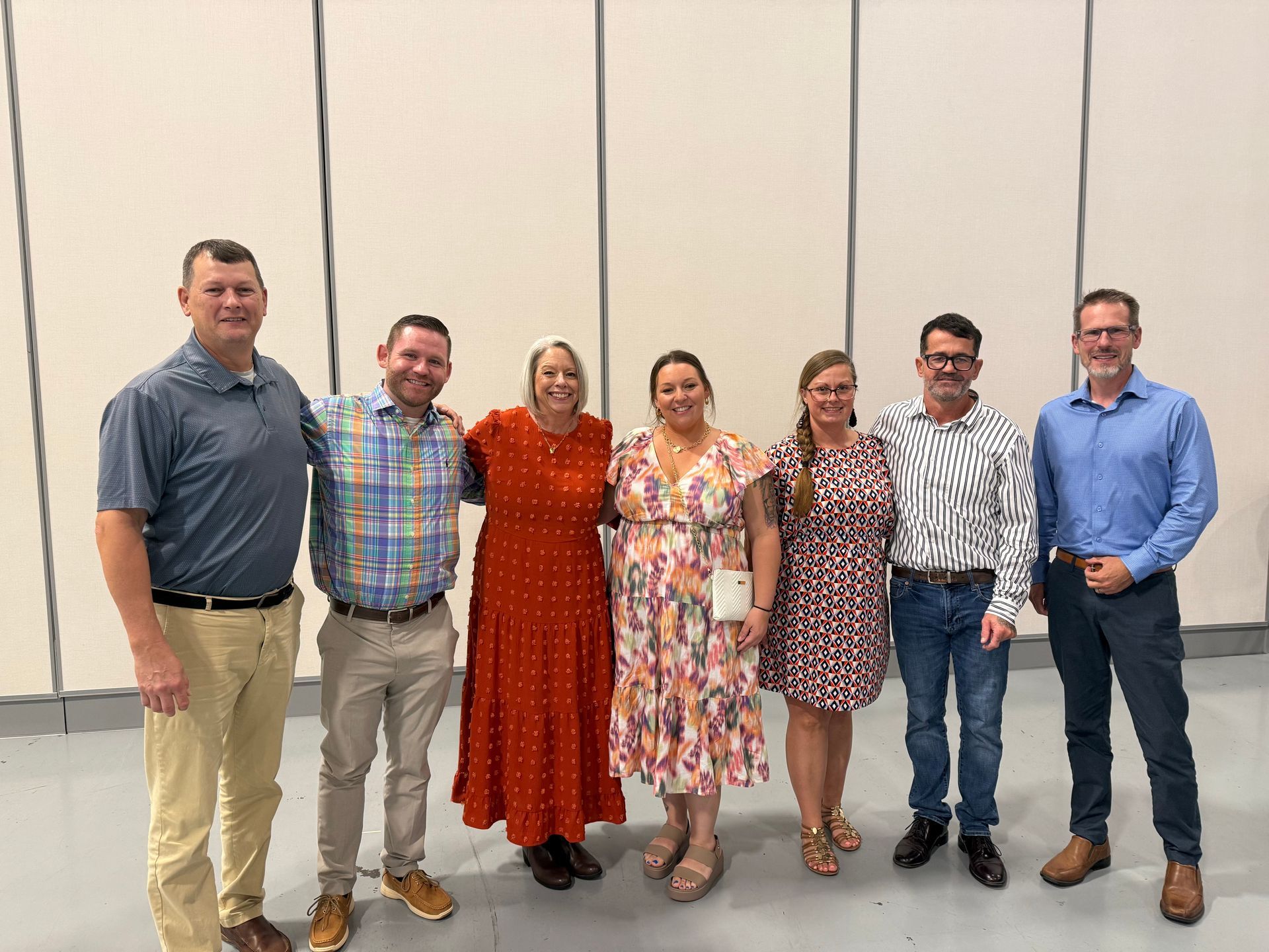 Seven people in nice clothing standing together and smiling. 