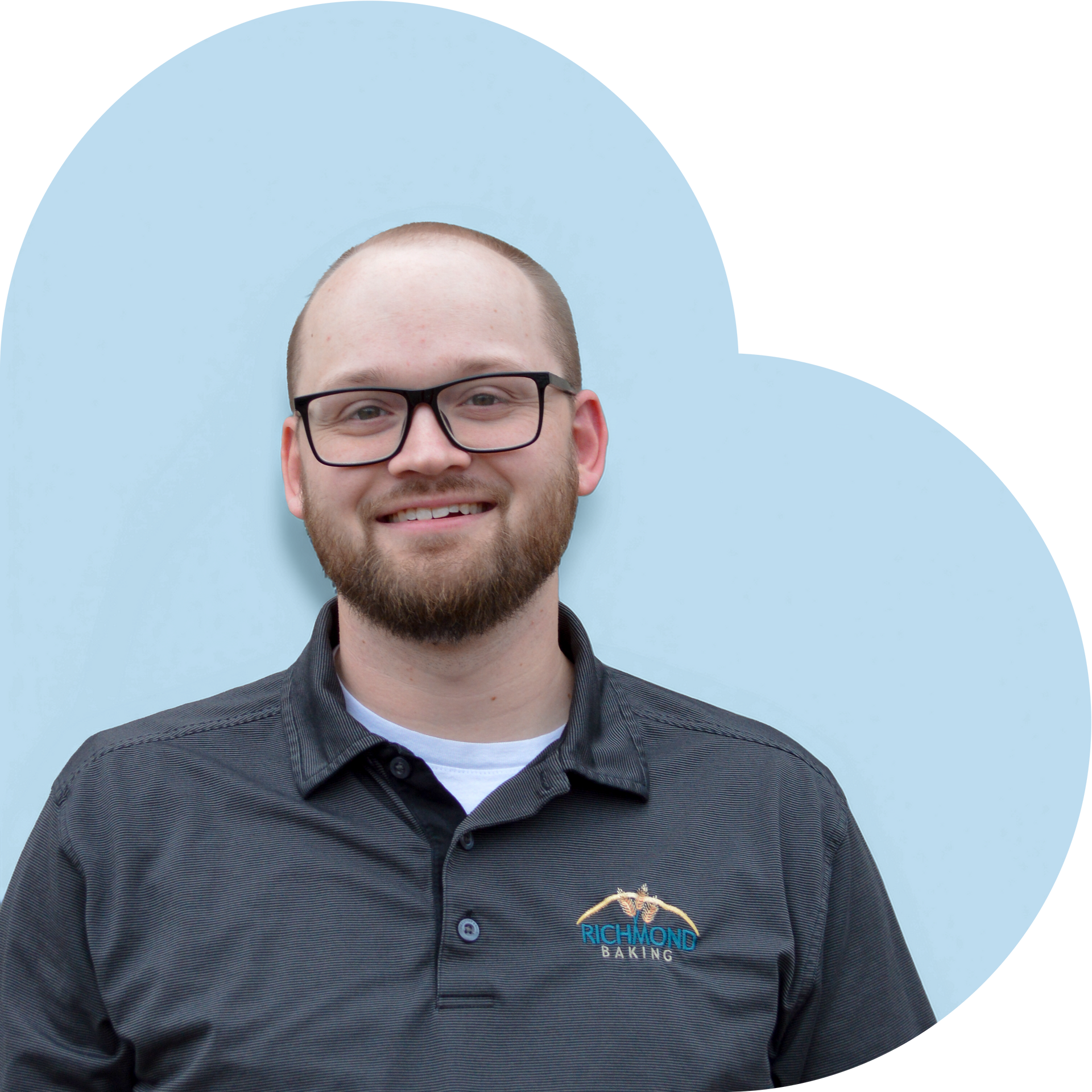 Man in a grey shirt smiling in front of a blue background.