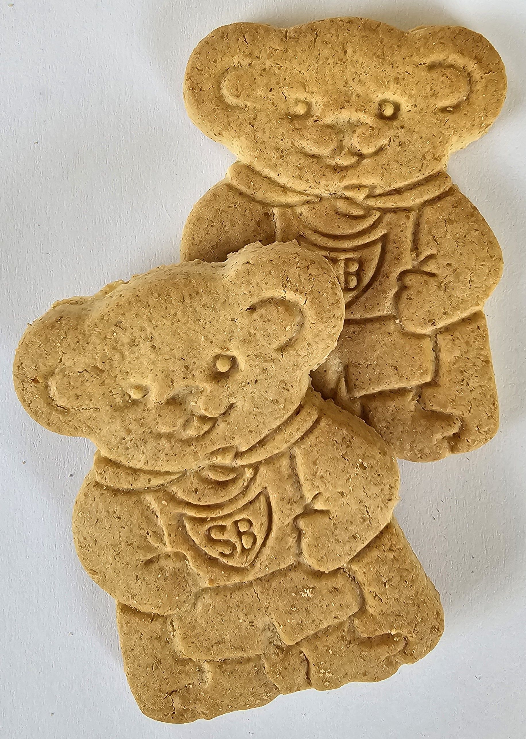 Two bear-shaped cookies, light brown with detailed faces and bibs bearing 