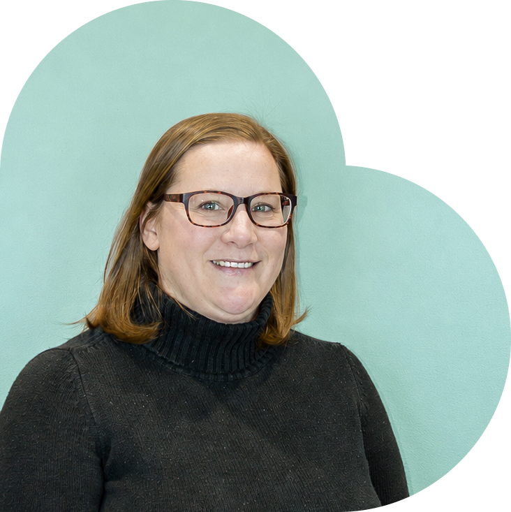 Woman in a black sweater smiling in front of a teal background.