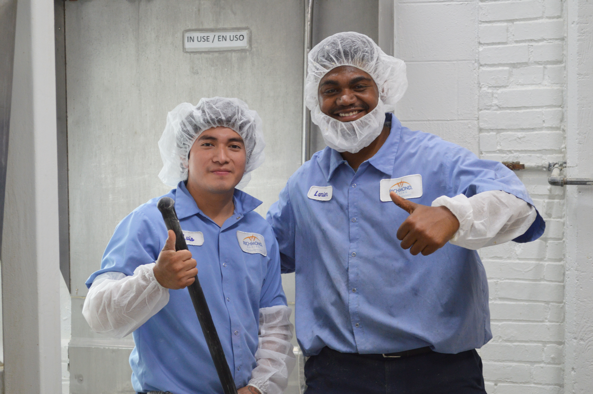 Two people in blue uniforms smiling and giving a thumbs up. 