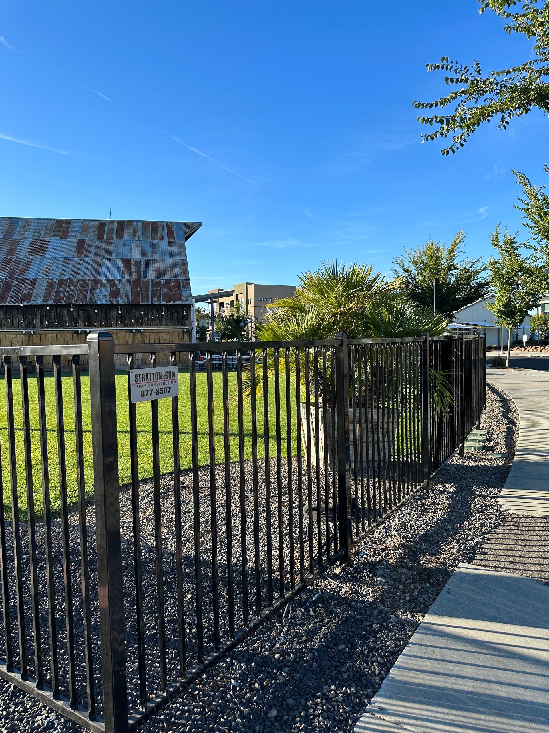 A large black fence is surrounding a white house.