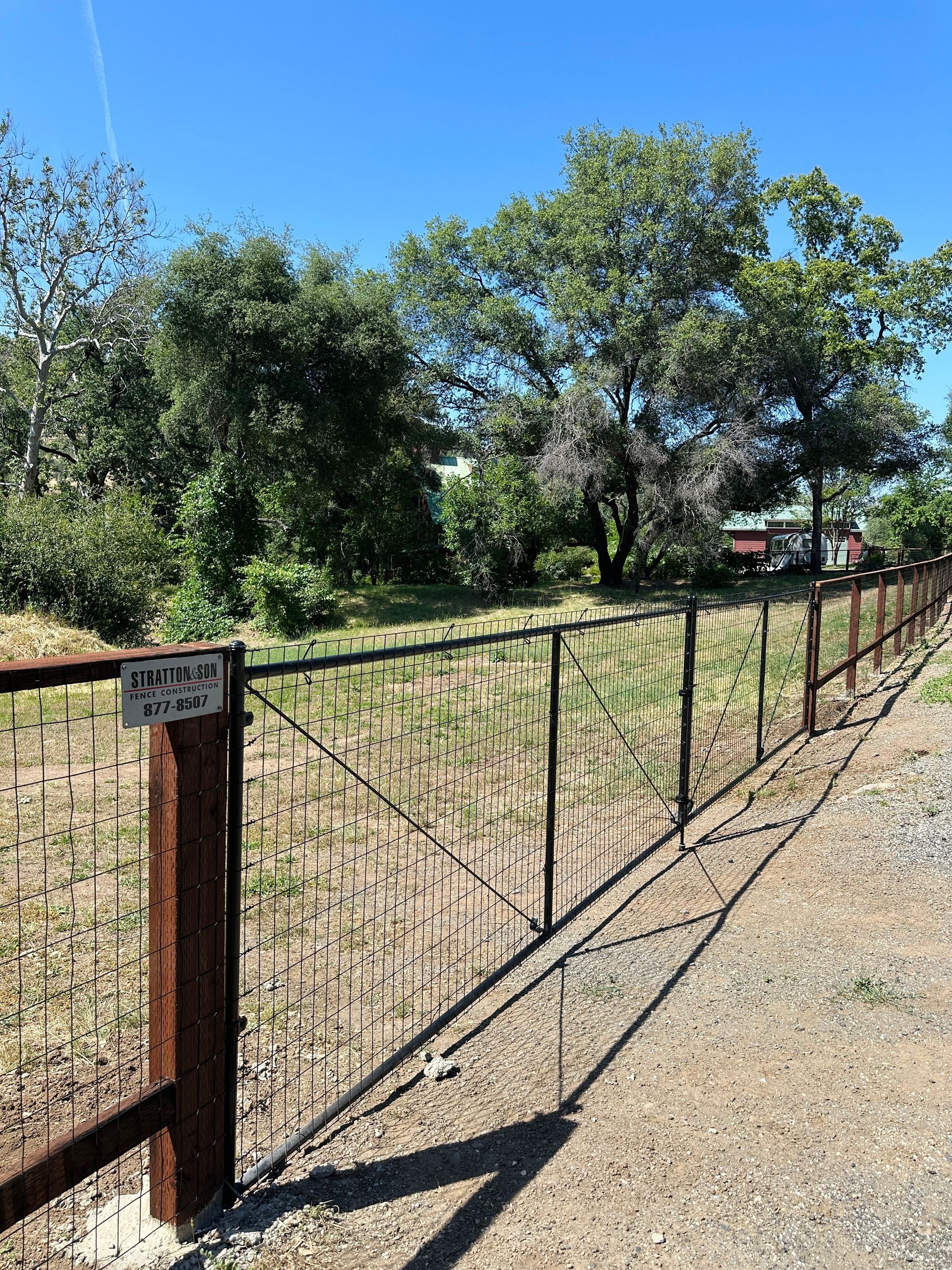 A black wrought iron gate is open to a driveway.