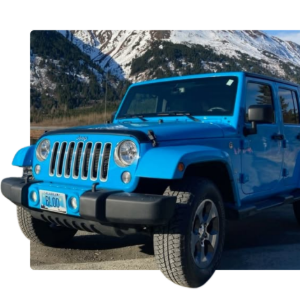 Bright blue Jeep Wrangler parked on a road with snowy mountains in the background