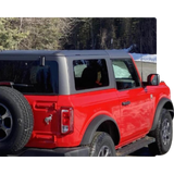 Red two-door off-road SUV with black soft top parked outdoors near snow and trees