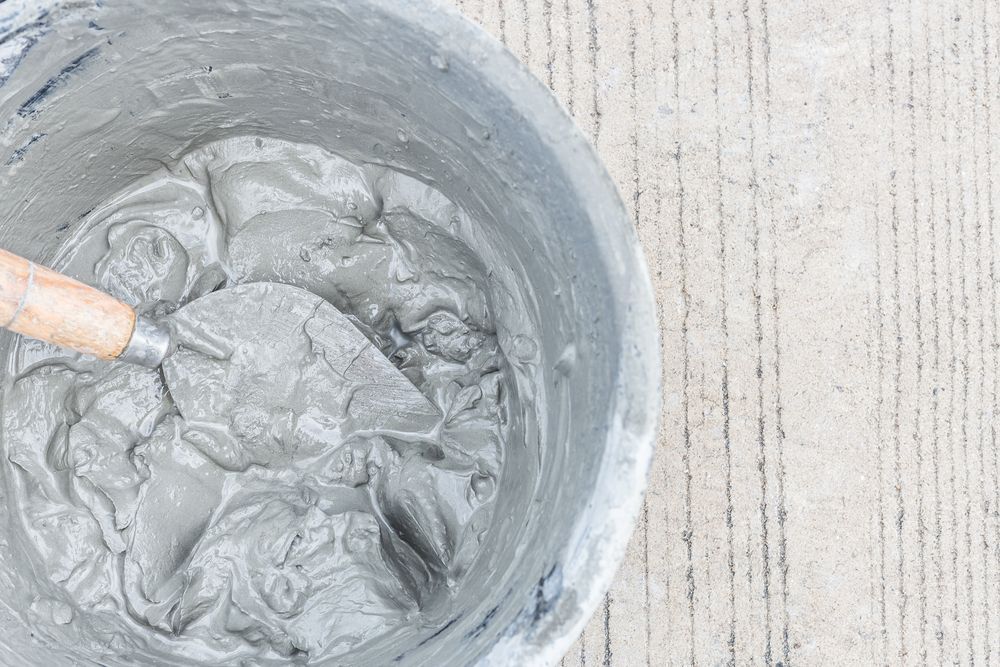 Bucket of Wet Cement with A Trowel, on A Concrete Surface — DGW Wholesale Timber & Hardware in Cessnock, NSW